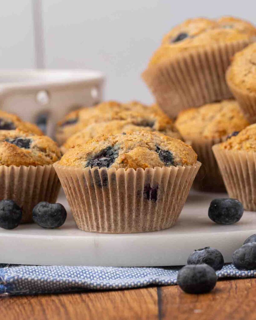 Blueberry muffins stacked on a white serving tray.