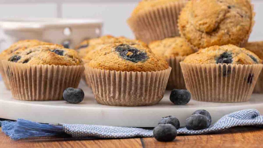 Blueberry muffins stacked on a white serving tray.