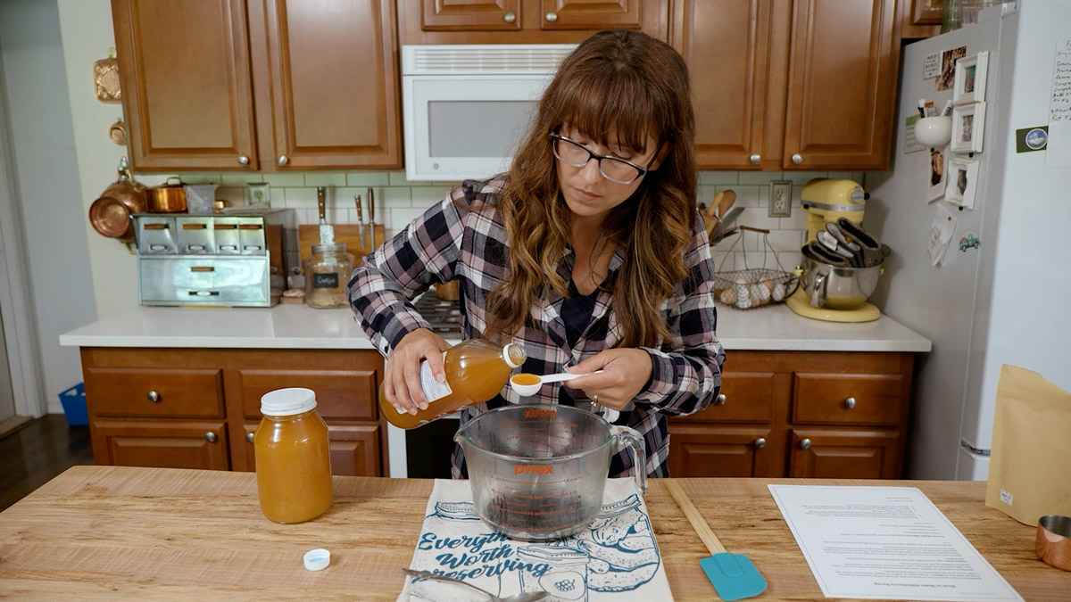 A woman measuring out apple cider vinegar.