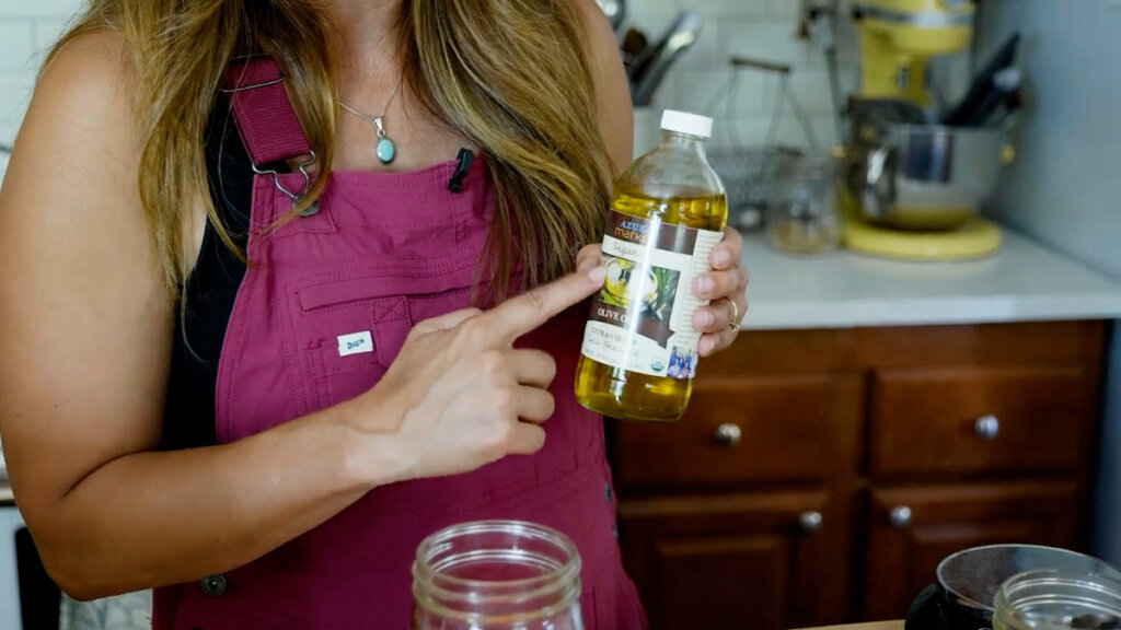 A woman holding a bottle of Azure Standard olive oil.