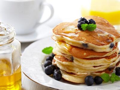 Blueberry pancakes stacked on a white plate.