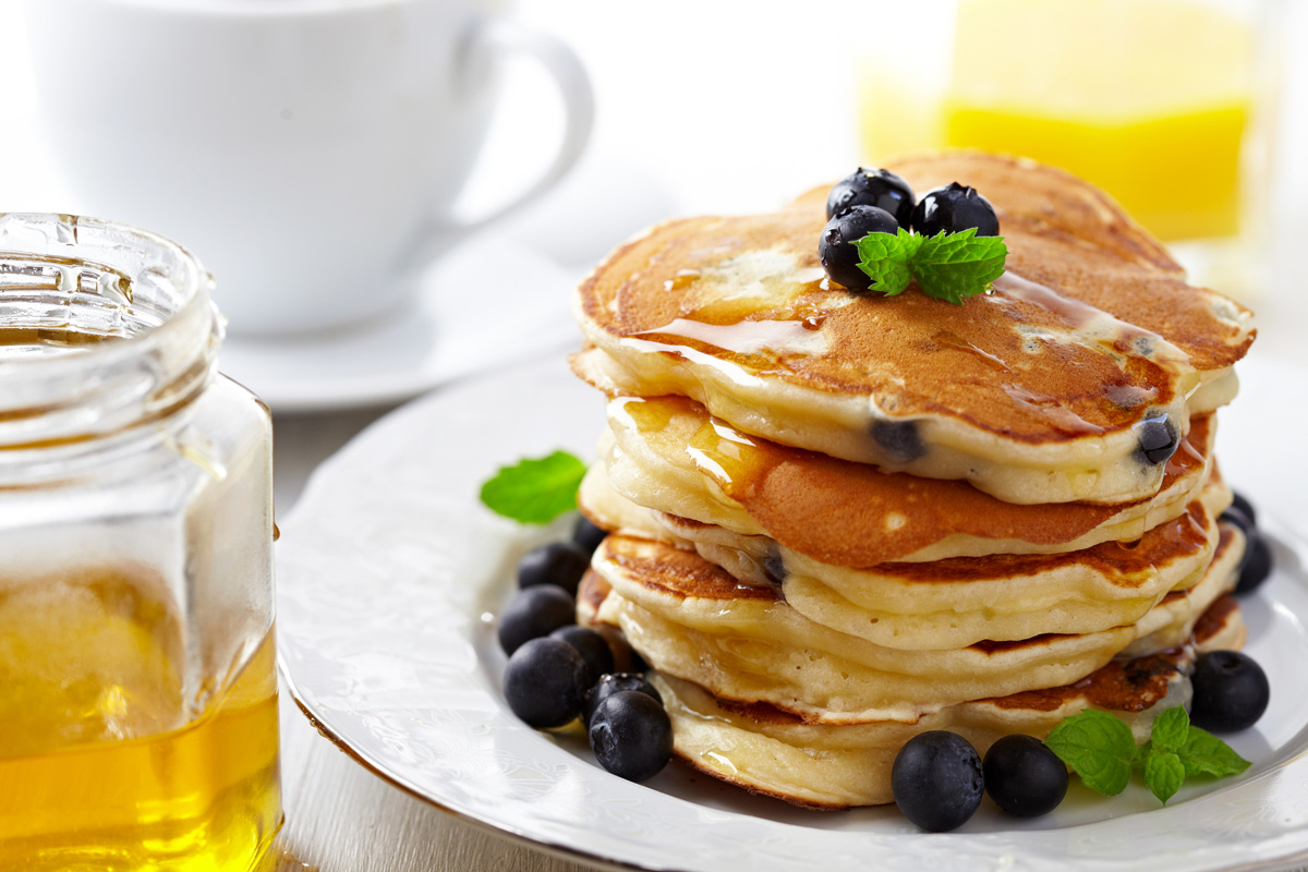Blueberry pancakes stacked on a white plate.