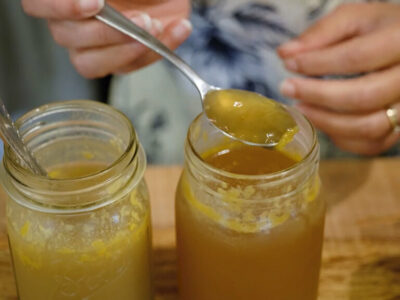 Two jars of bone broth and a spoonful of gelatinous broth.