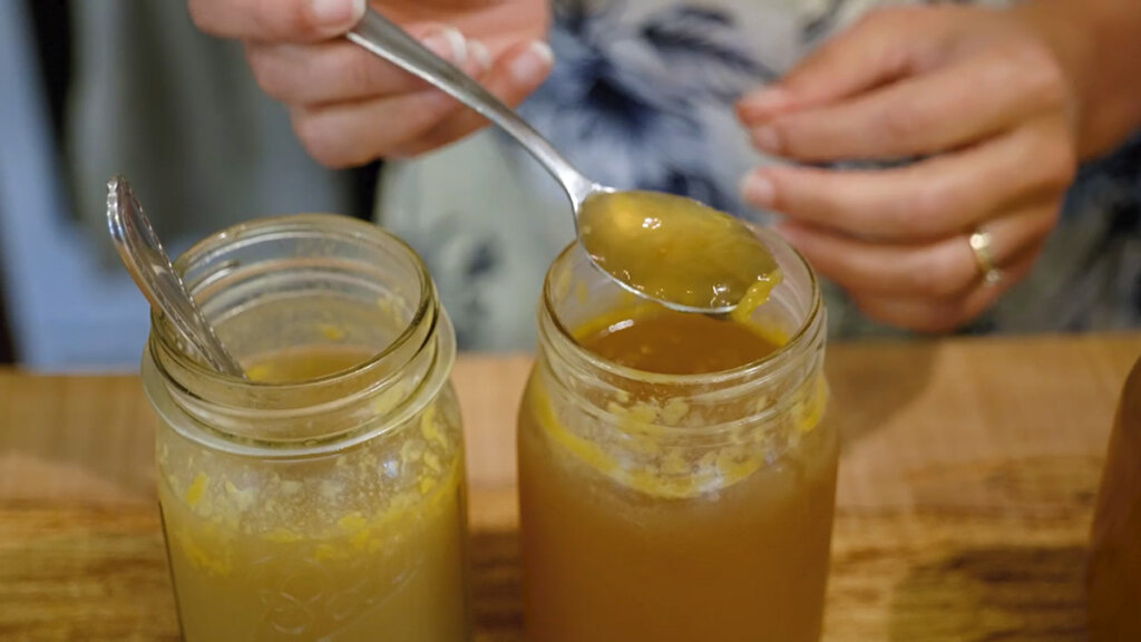Two jars of bone broth and a spoonful of gelatinous broth.