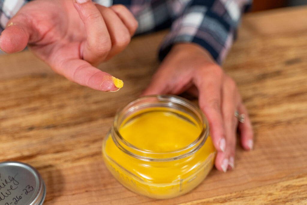 A woman dipping her finger into homemade healing salve.