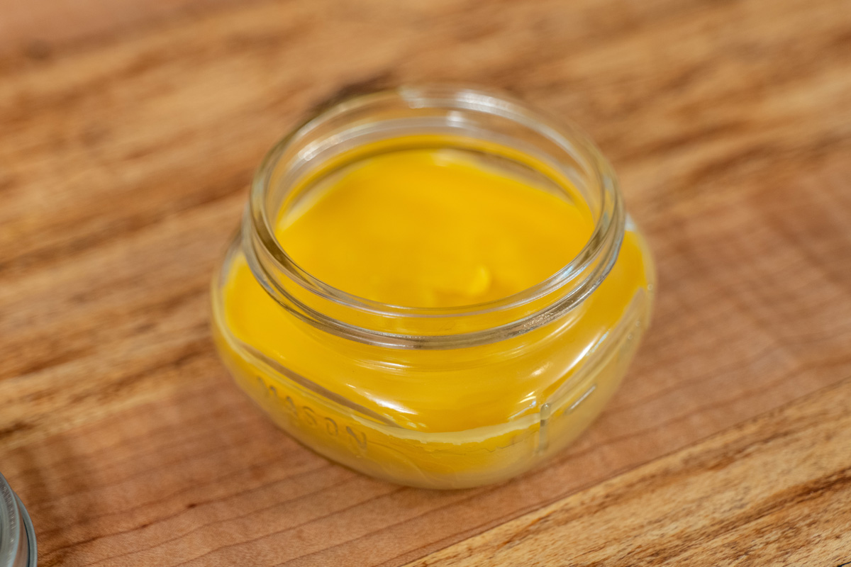 A jar of homemade healing salve on a wooden counter.