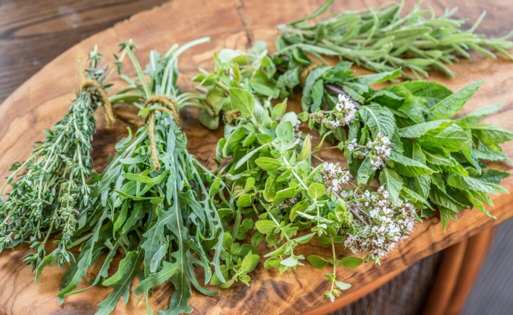 Bundles of fresh herbs laying on a wooden table.