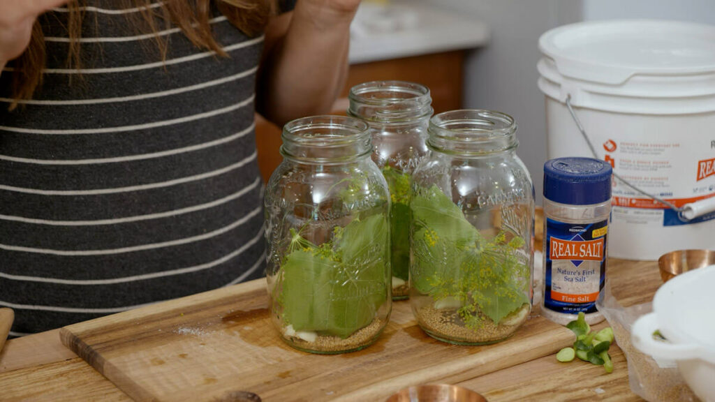 Grape leaves and spices in a jar for homemade pickles.