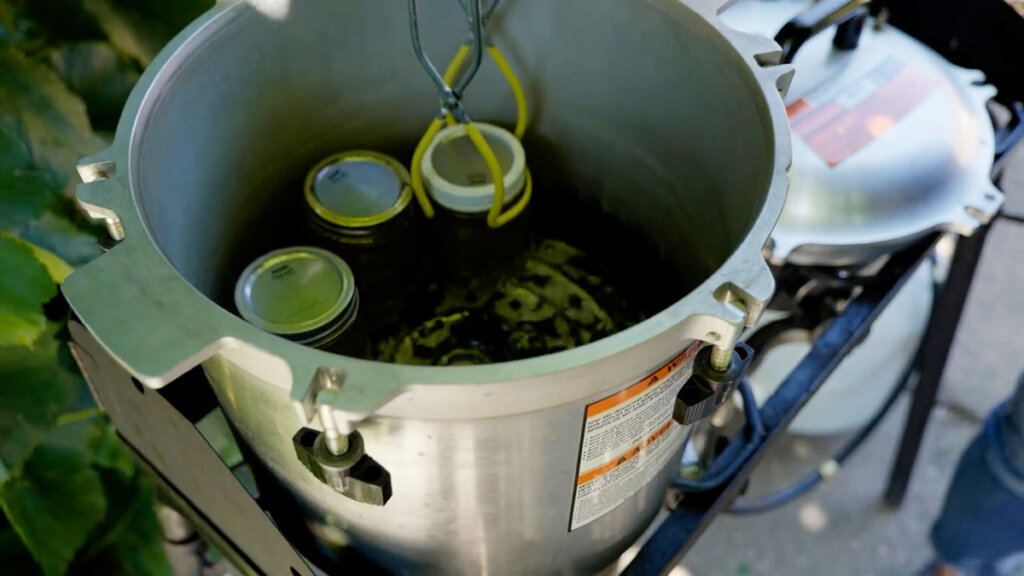 Three jars of broth inside a pressure canner.