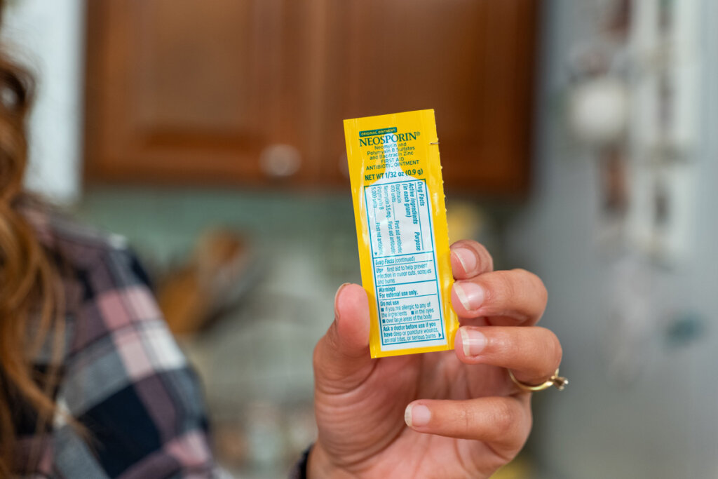 A woman holding up a tube of Neosporin.