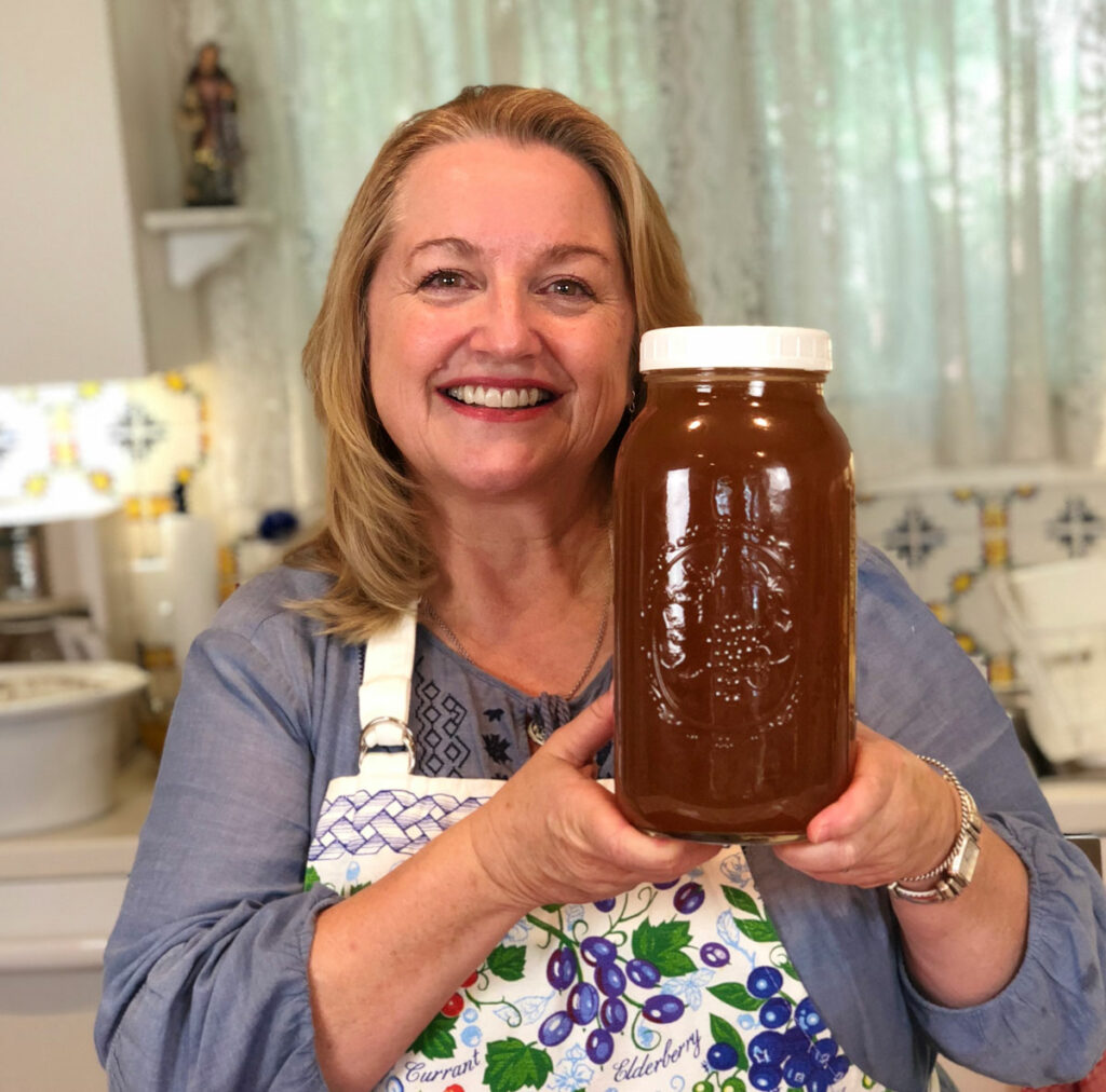 A woman holding a half-gallon jar of bone broth.