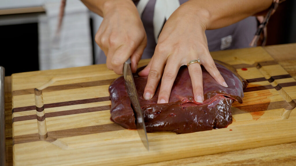 A woman slicing beef liver.