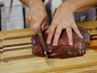 A woman slicing beef liver.