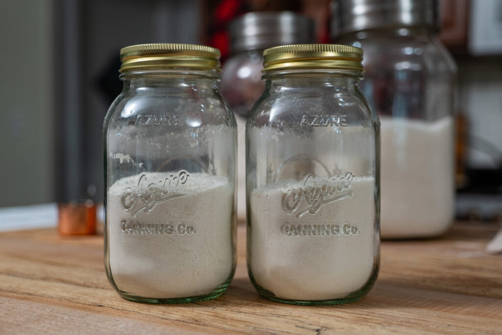 Two jars of homemade cake mix on a wooden counter top.