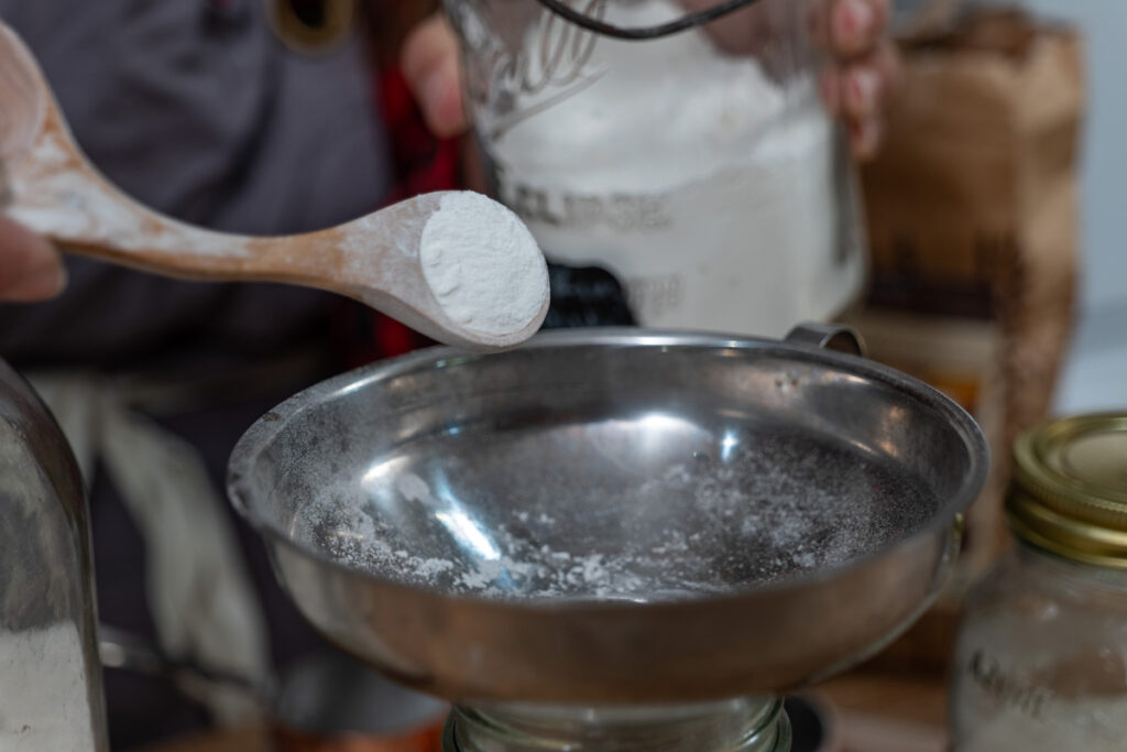 Ingredients being poured into a jar for homemade cake mix.