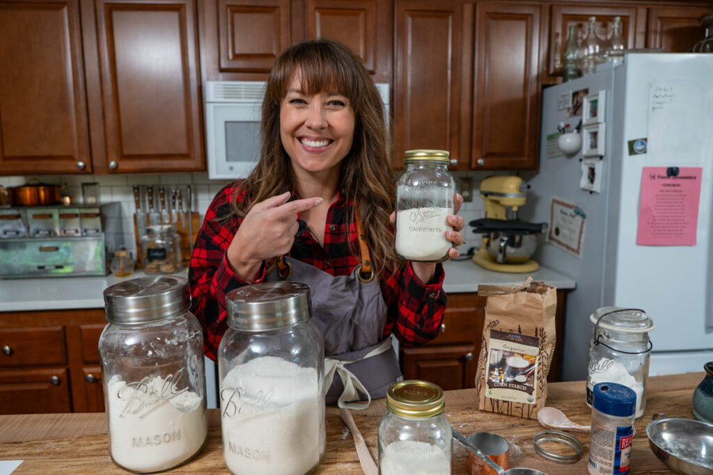 A woman holding up a Mason jar filled with homemade cake mix.
