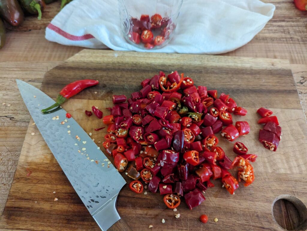 Fresh hot peppers chopped on a wooden cutting board.