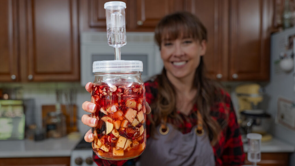 A woman holding fermented Cranberry sauce in a jar.