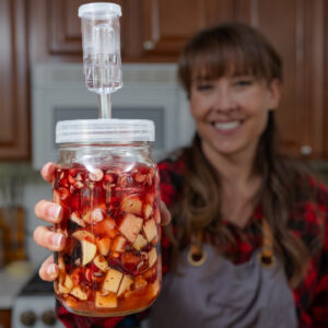 A woman holding fermented Cranberry sauce in a jar.