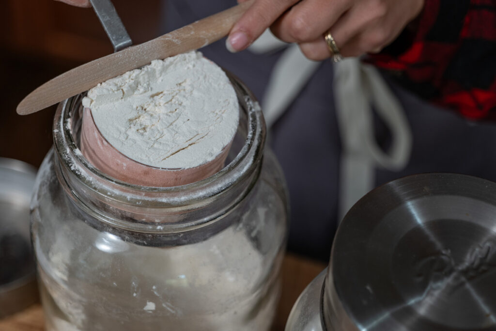 Ingredients being poured into a jar for homemade cake mix.