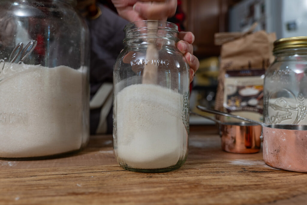 A wooden spoon stirring the ingredients inside a Mason jar.