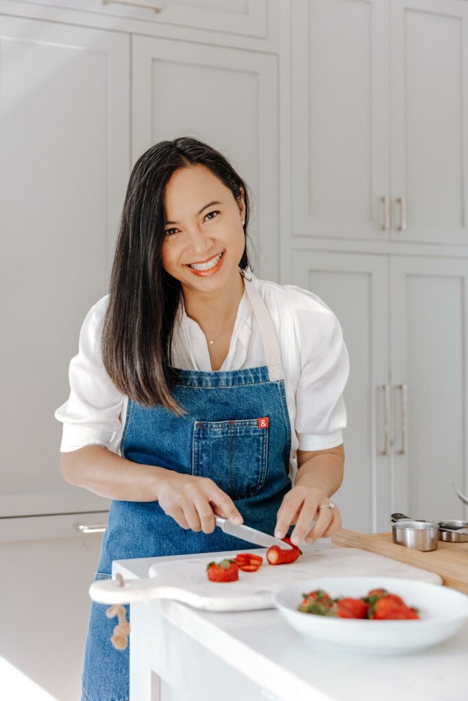 A woman chopping strawberries in the kitchen.