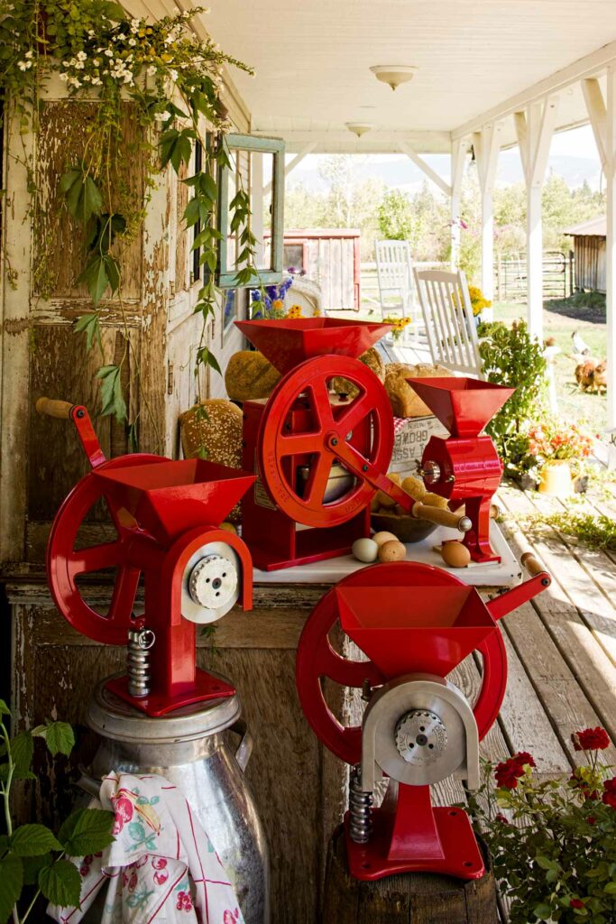 Various GrainMaker hand-crank mills on a porch.