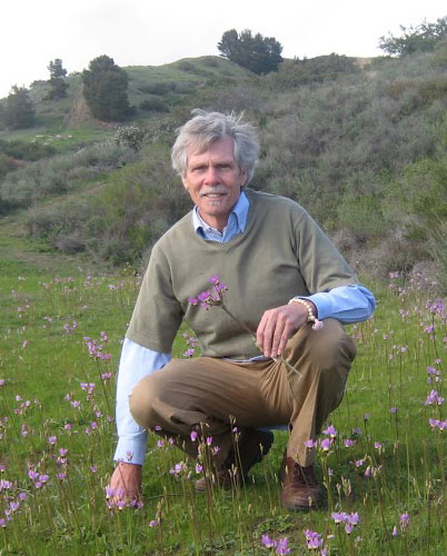 Dr. Christopher Hobbs crouching in a field of wild flowers.