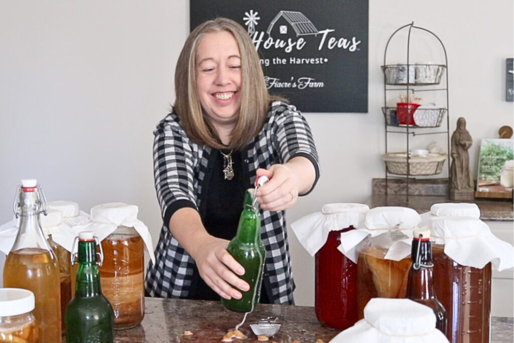 A woman opening a grolsch bottle with fizzy kombucha coming out.