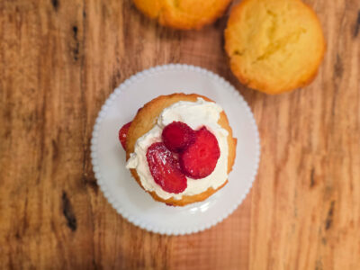homemade strawberry short cake on a white plate sitting on a wooden counterop