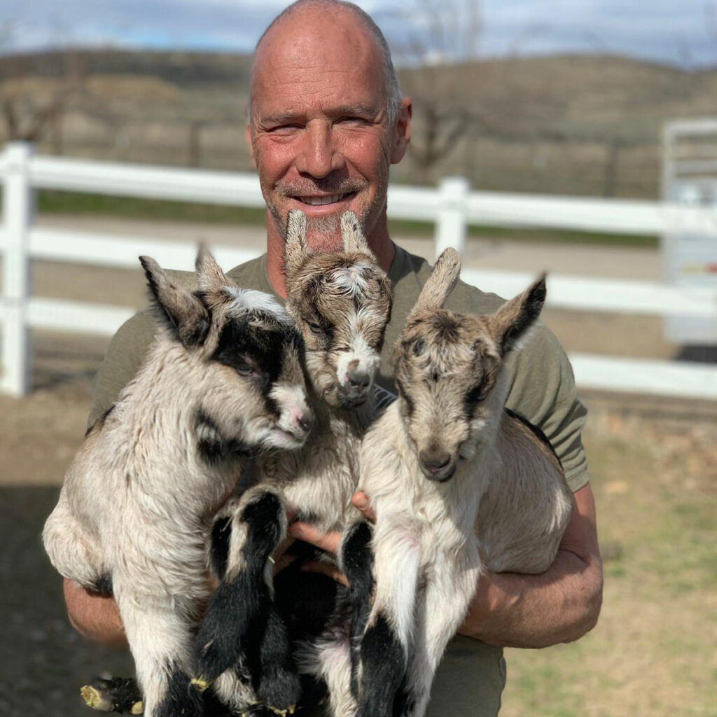 A man holding three baby goats.