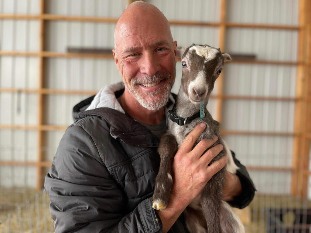 A man holding a baby goat.