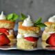 Stacks of homemade strawberry shortcake on a platter with mint and fresh strawberries