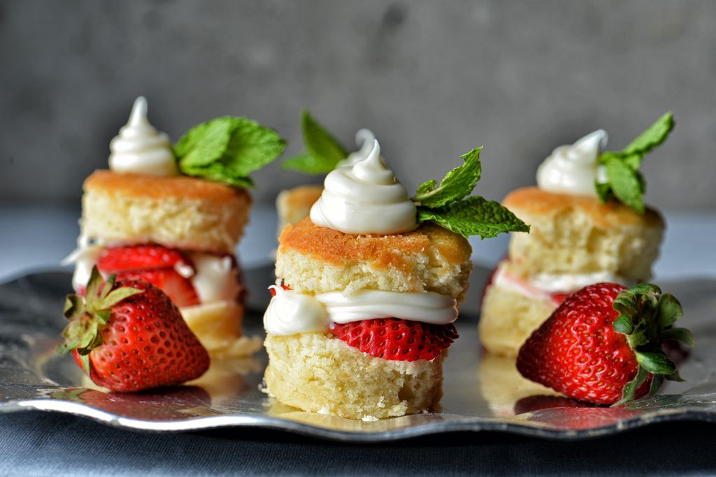 Stacks of homemade strawberry shortcake on a platter with mint and fresh strawberries