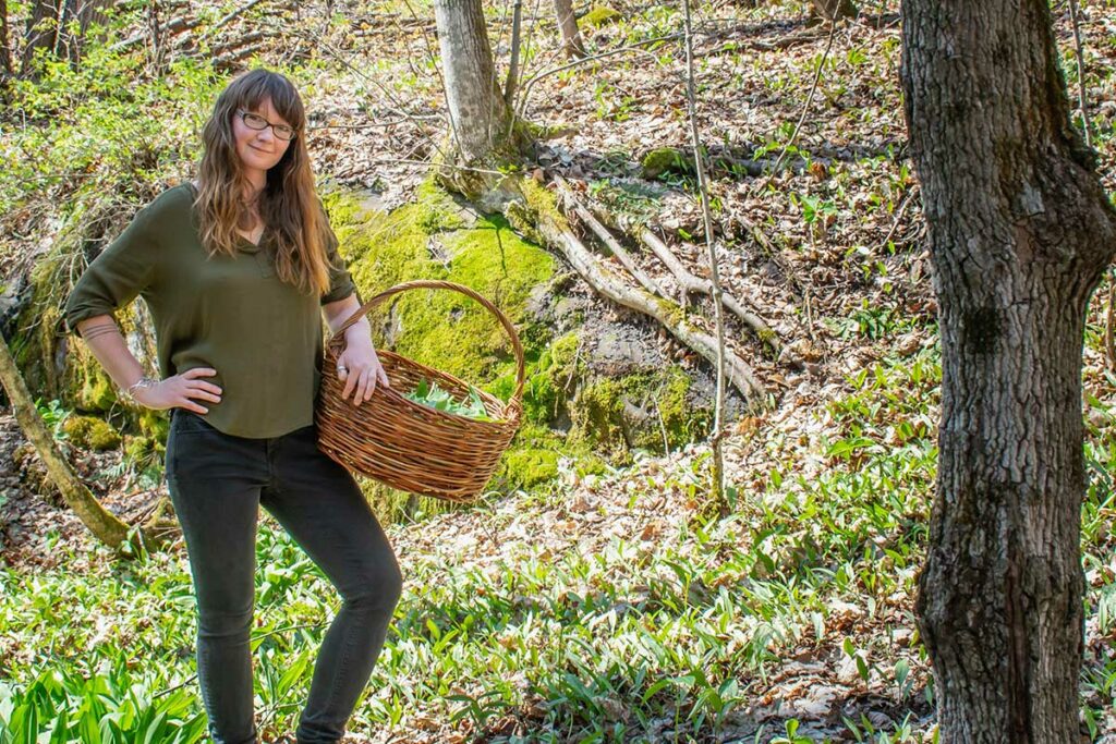 A woman holding a basket in the woods.