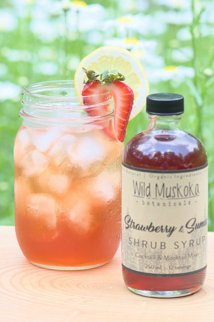 An ice-cold shrub next to a bottle of shrub syrup.