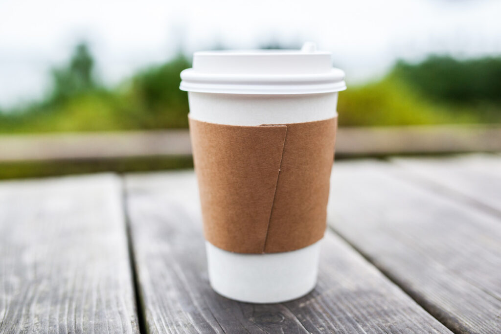 A to go coffee cup on a wooden deck.