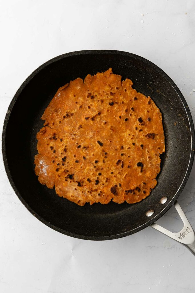 A sweet potato tortilla cooking in a pan.