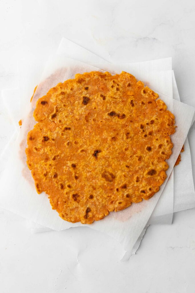 A stack of sweet potato tortillas with parchment paper between each layer.