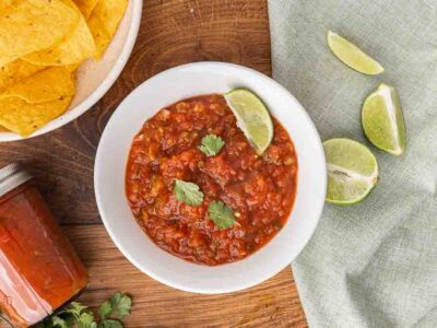 A white bowl full of fermented salsa garnished with cilantro and a wedge of lime.