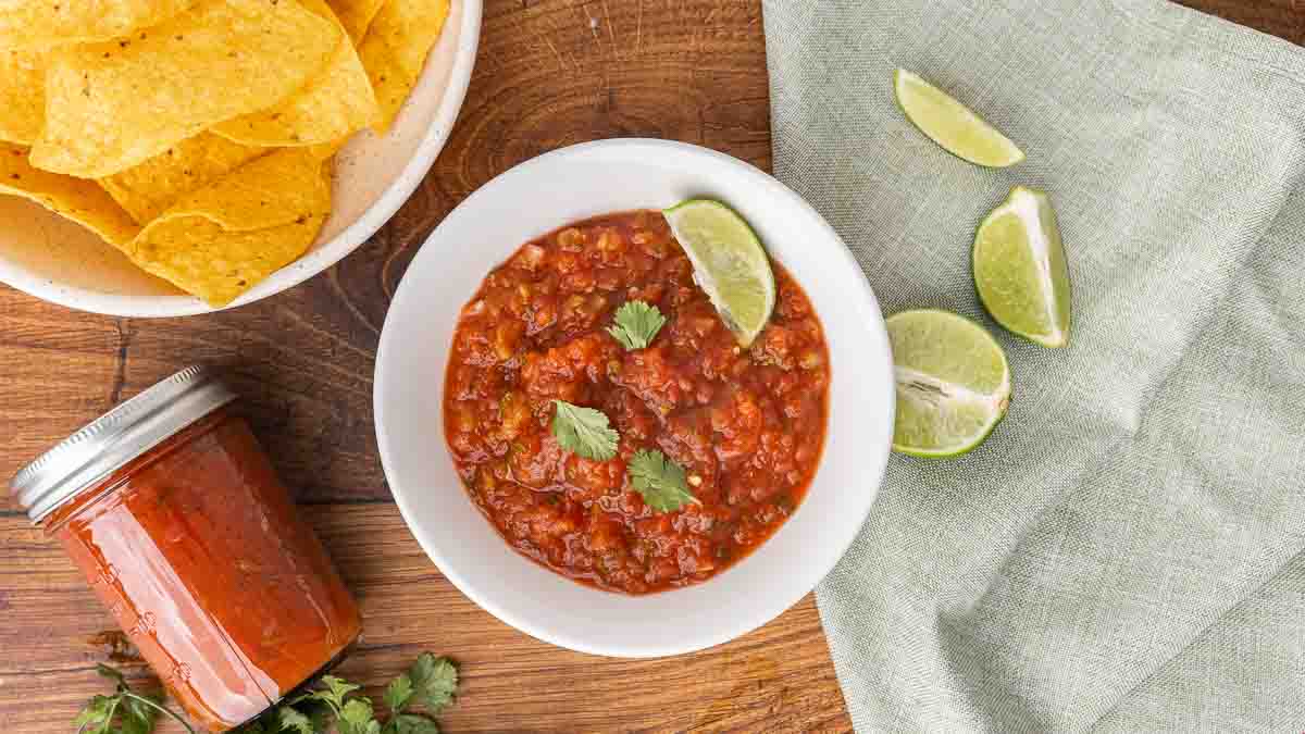 A white bowl full of fermented salsa garnished with cilantro and a wedge of lime.