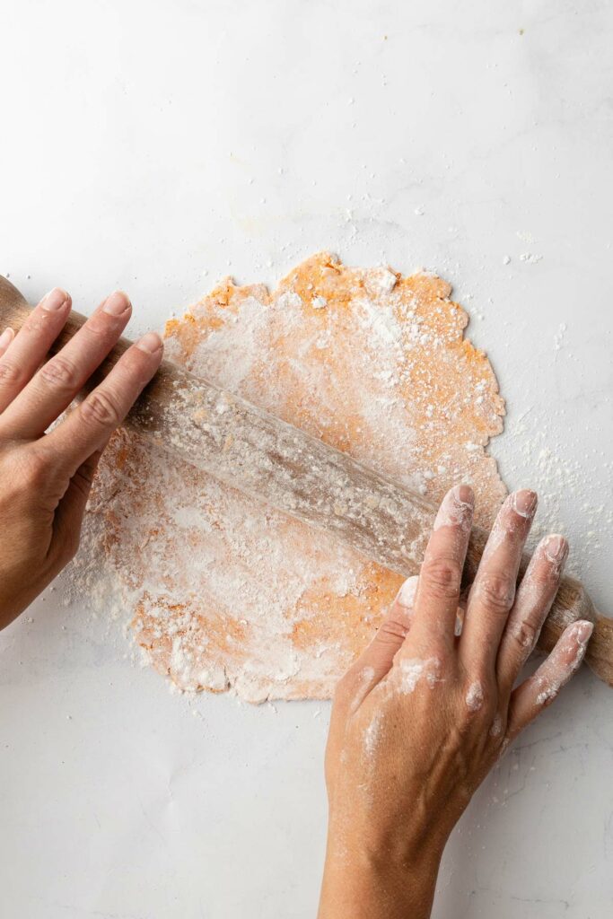 A sweet potato tortilla being rolled out with a rolling pin.