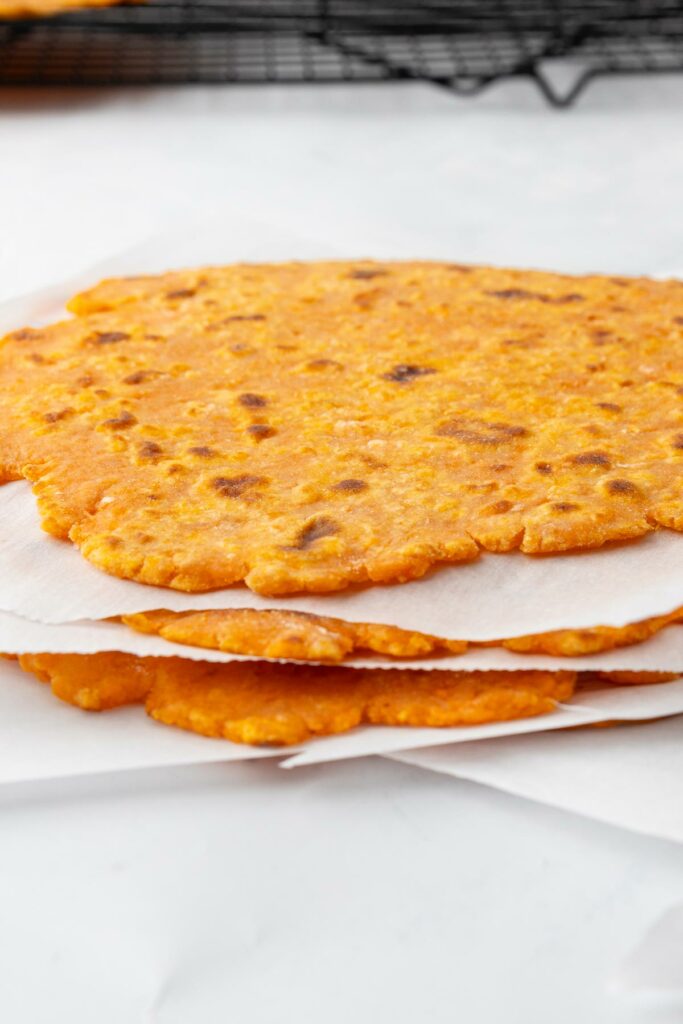 A stack of sweet potato tortillas with parchment paper between each layer.