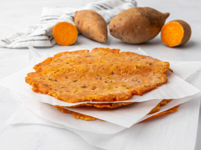 A stack of sweet potato tortillas with parchment paper between each layer.