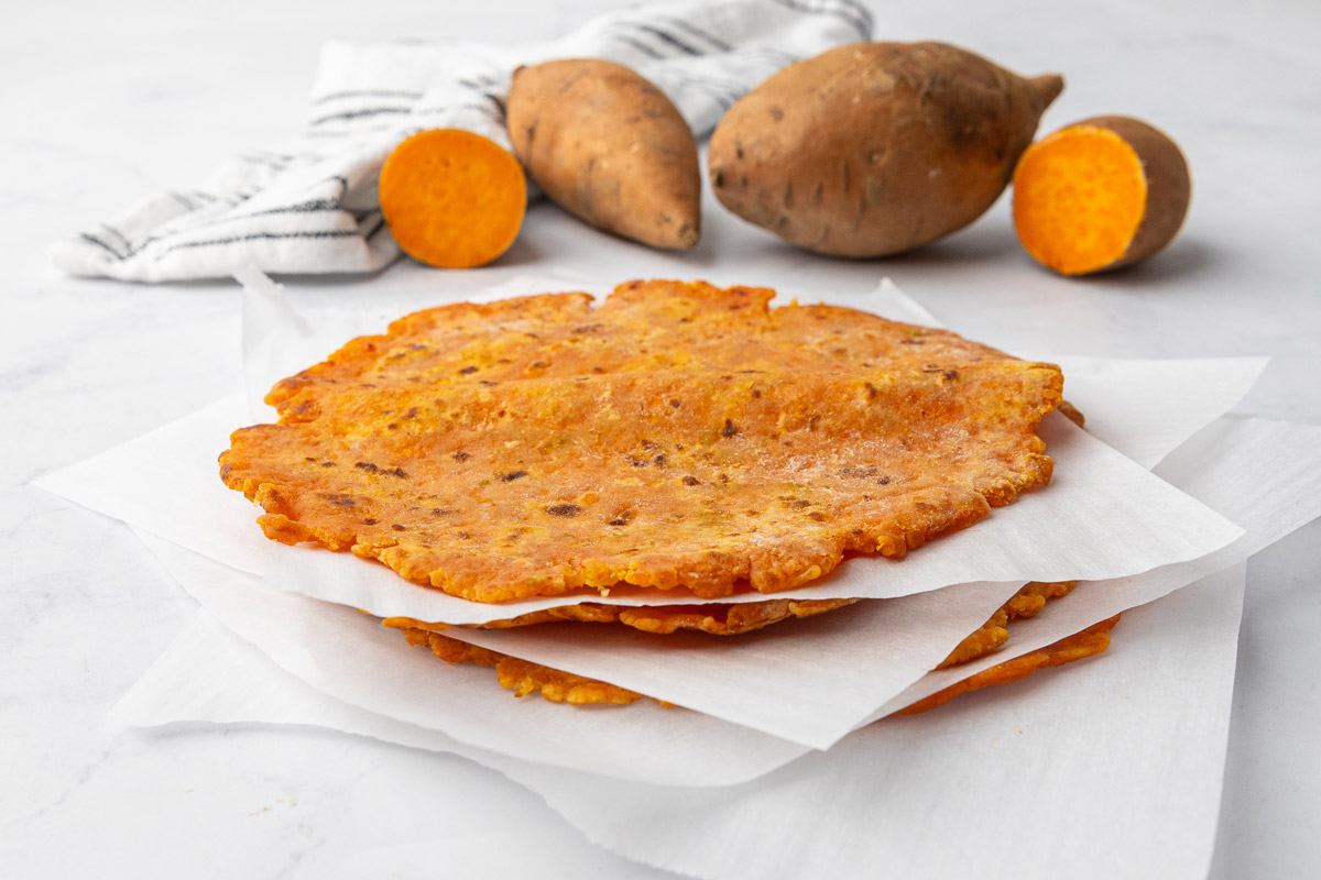 A stack of sweet potato tortillas with parchment paper between each layer.