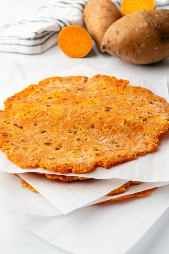 A stack of sweet potato tortillas with parchment paper between each layer.