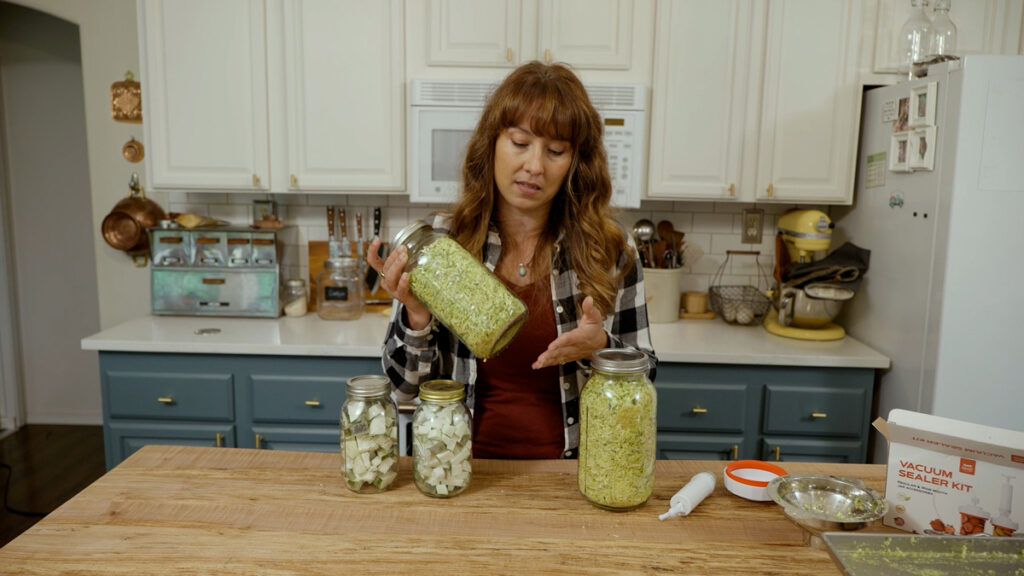 A woman in the kitchen with jars of freeze dried zucchini.