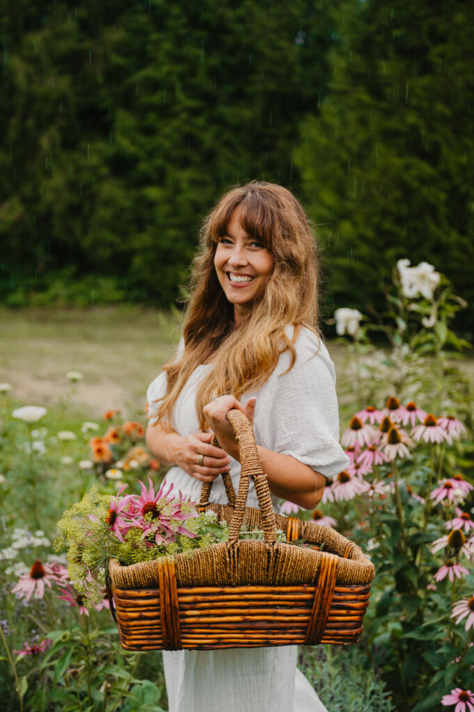 A woman holding a basket full of medicinal herbs and flowers.