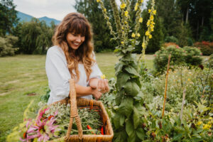 Woman harvesting medicinal herbs and flowers from a garden.