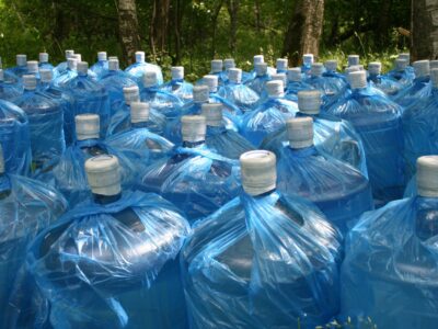 Multiple five gallon jugs of water sitting outside for storage.